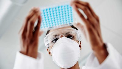 medical researcher with mask carries tray of samples