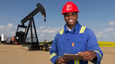 happy oil worker in front of oil production equipment