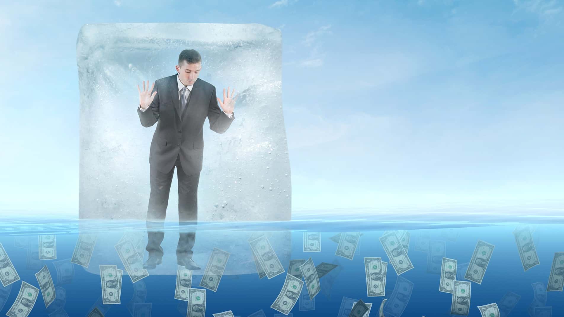 businessman in trading halt frozen in ice cube floating on a sea of money