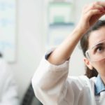 medical research laboratory assistant examines solutions in test tubes