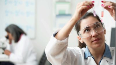 medical research laboratory assistant examines solutions in test tubes