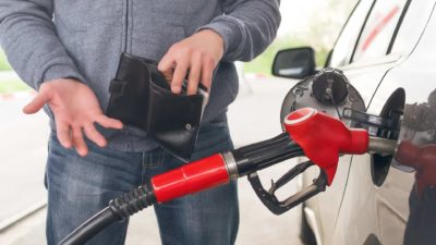person pumping petrol in a car holding an empty wallet