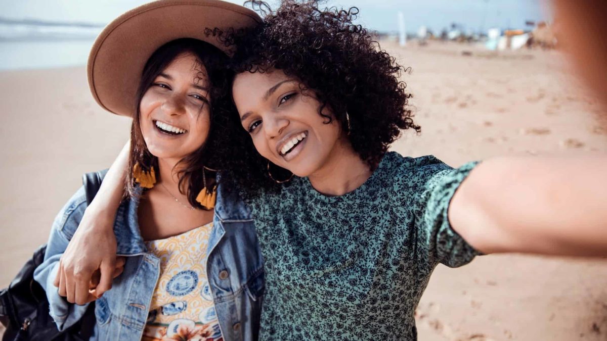 Two young girls on the beach taking a selfie