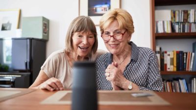 Two elderly women using technology showing joy.