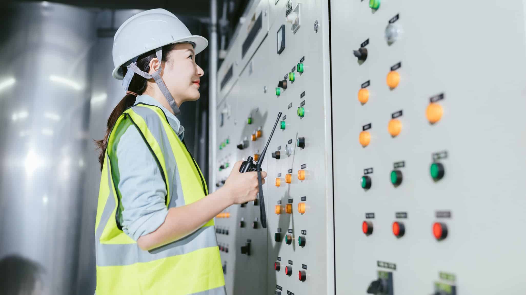 Female power plant worker looks at switchboard