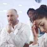 Scientists in white coats look disappointed.