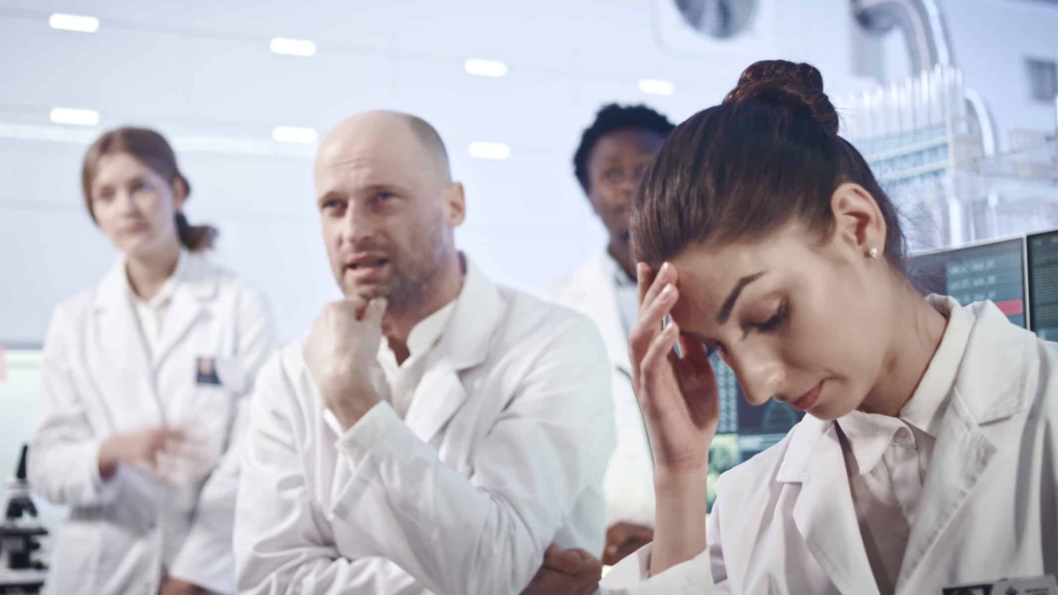 Scientists in white coats look disappointed