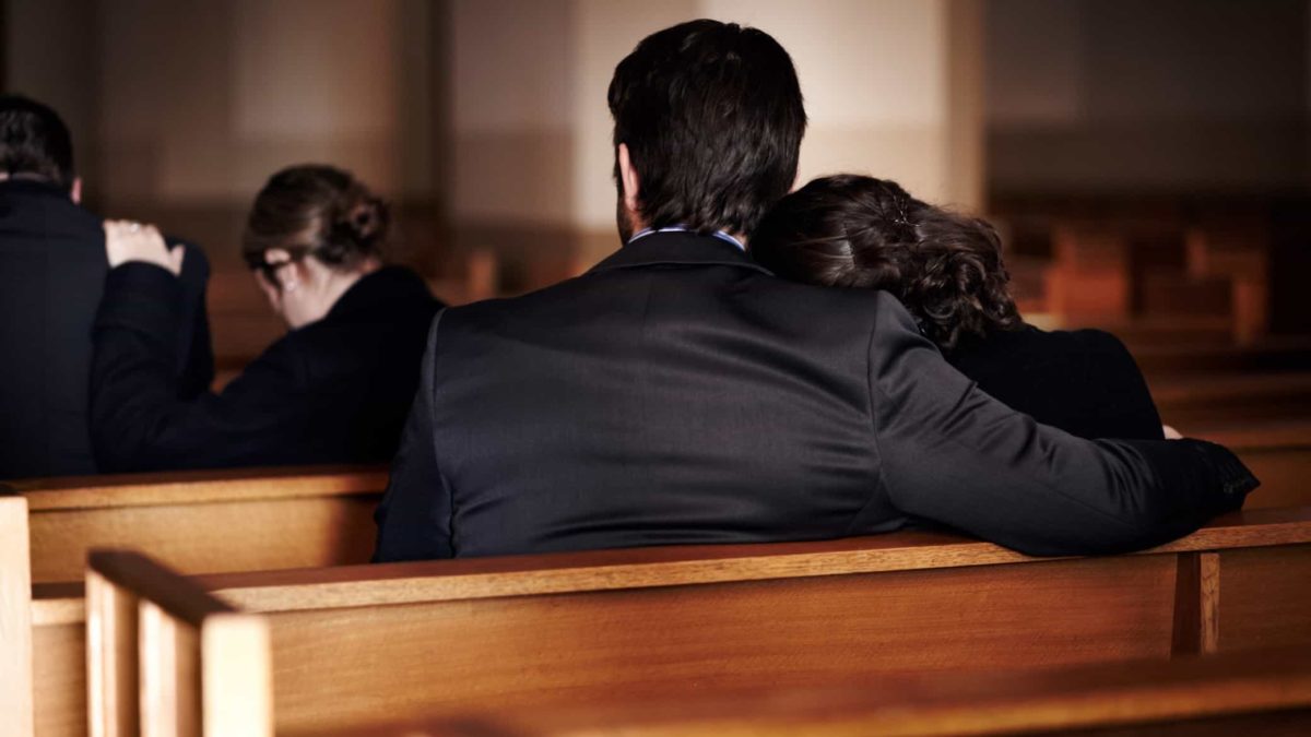 Two people comfort each other at funeral