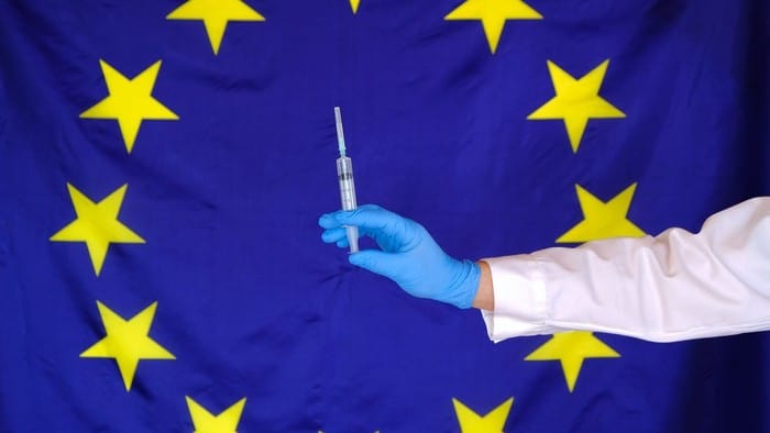 European Union flag with a person holding a vaccine in the middle