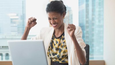 Woman cheering in front of laptop as she watches the Metal Hawk share price rise