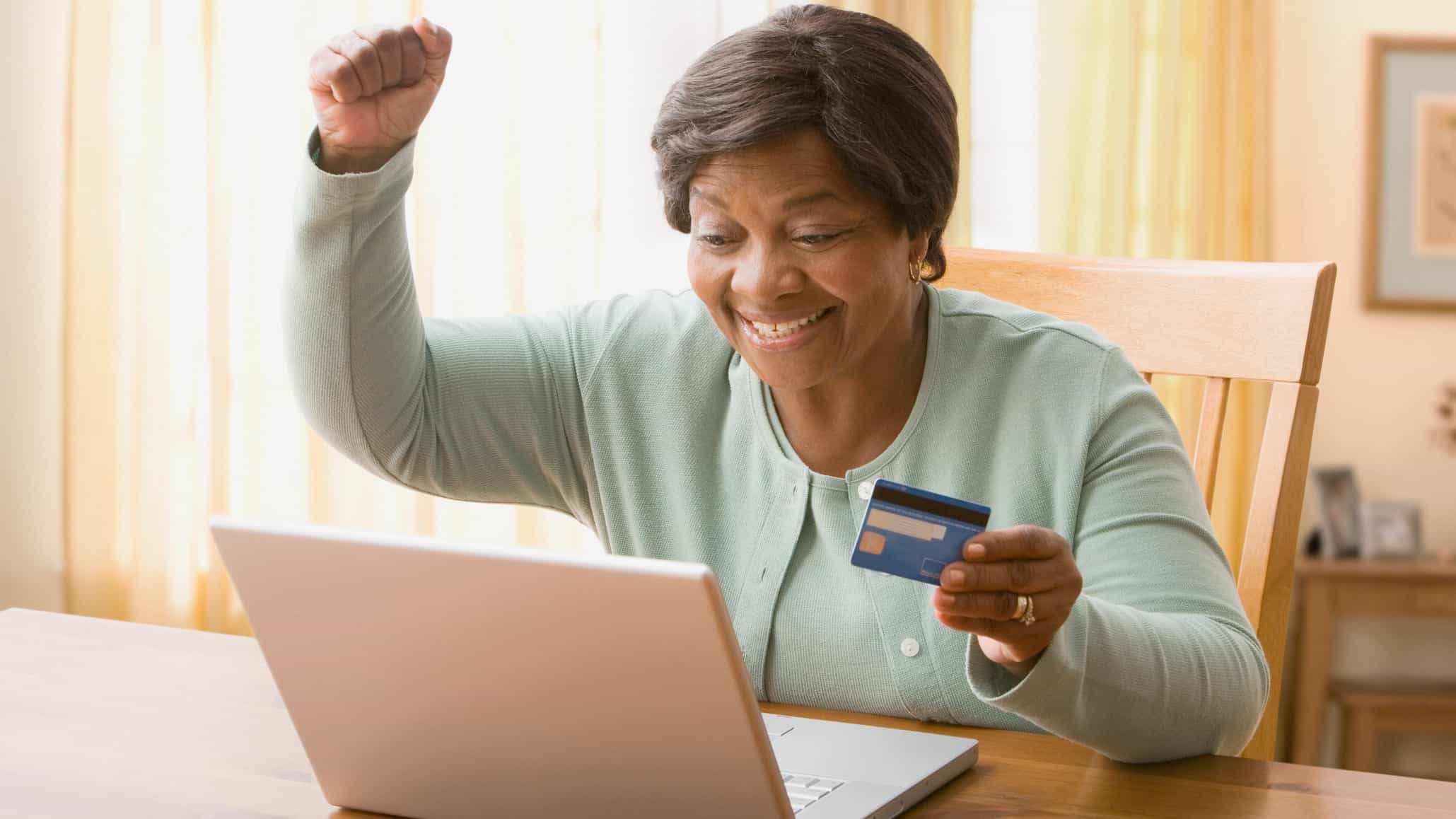Woman cheers as she shops online with credit card