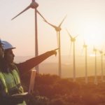 Workers at a wind farm in front of wind turbines.