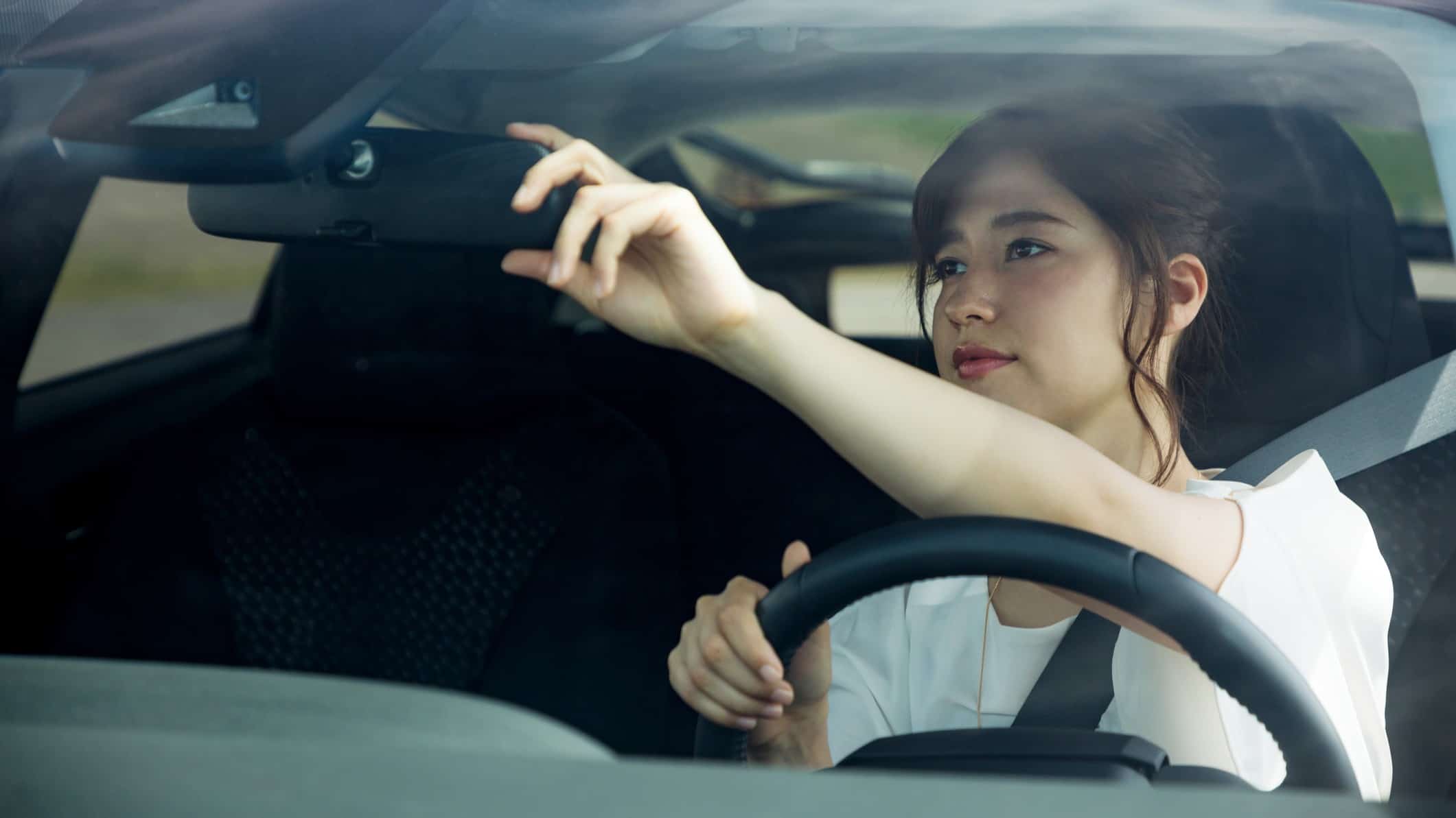 woman looking in the rea vision mirror of her car