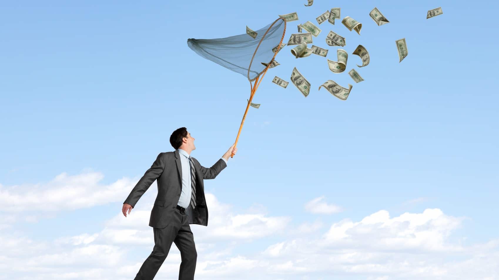 investor holding a net and trying to catch money flying around in the wind.