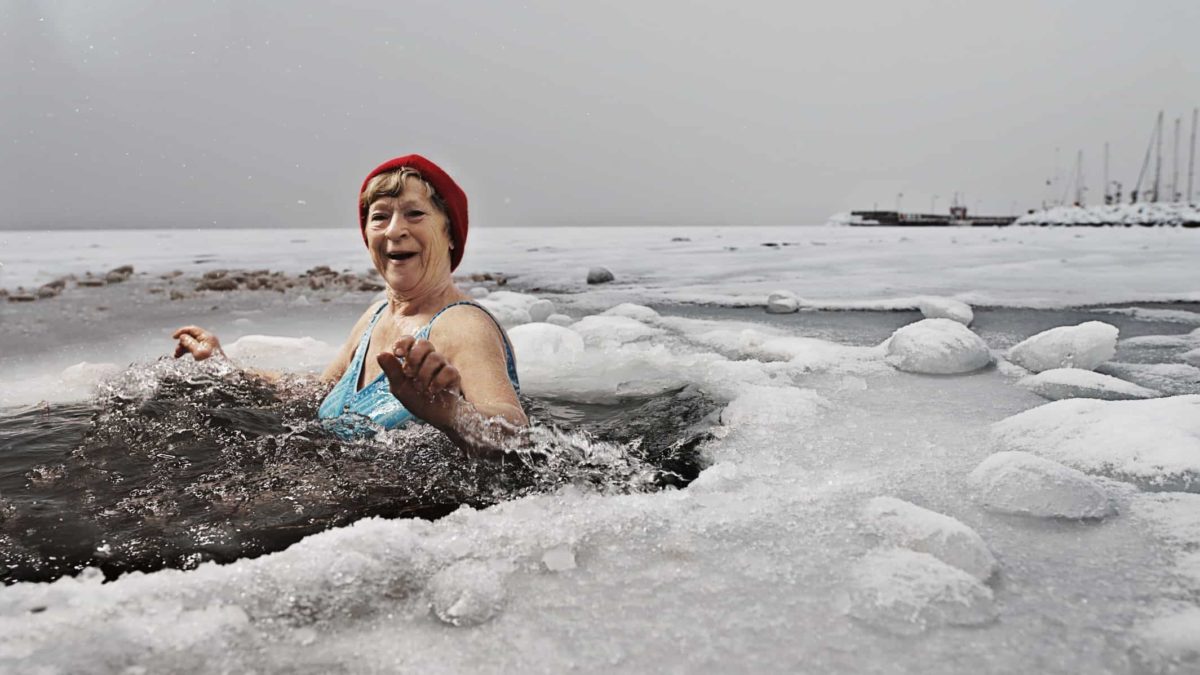 A happy woman having a swim in a pool in the middle of a frozen lake.