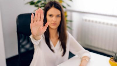 woman sitting at desk holding hand up in stop motion