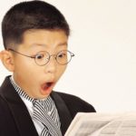 surprised child reading all about asx 200 shares in a newspaper