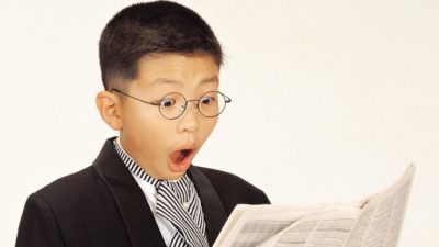 surprised child reading all about asx 200 shares in a newspaper