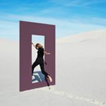 a woman jumping through a window of opportunity in sand dunes