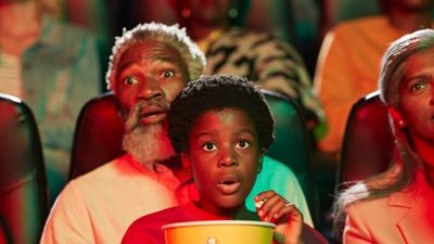 father and son eating popcorn and enjoying a movie in a cinema