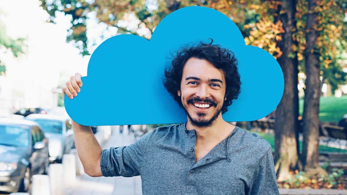 Man happy to be holding a blue cloud representing cloud computing.