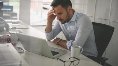 concerned and worried man looking at computer and monitoring falling share price