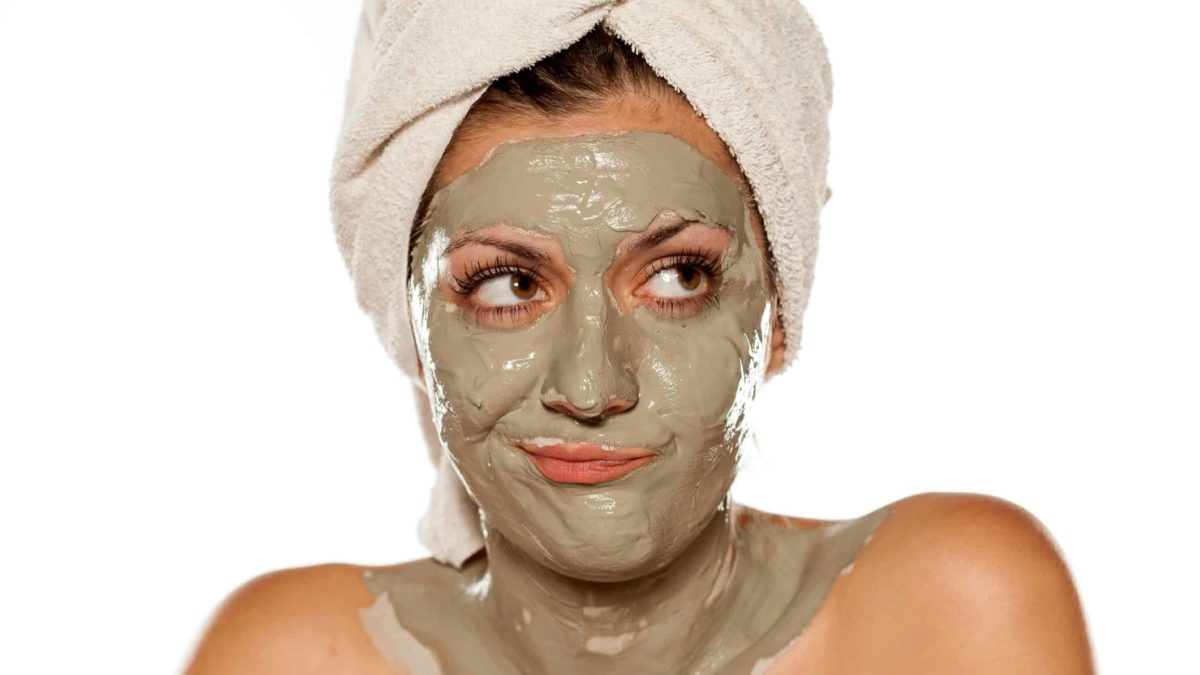 A woman wearing a beauty mask on her face shrugs and looks unhappy.