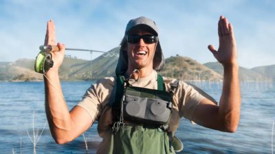 A recreational fisherman holds a fishing rod with his hands apart indicating it was this big with a smile on his face.