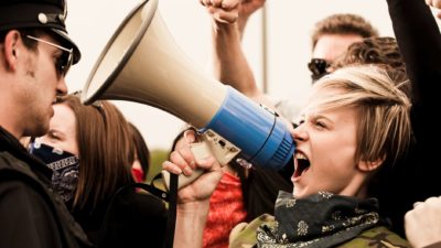Woman shouts into a megaphone amongst a group of protesters