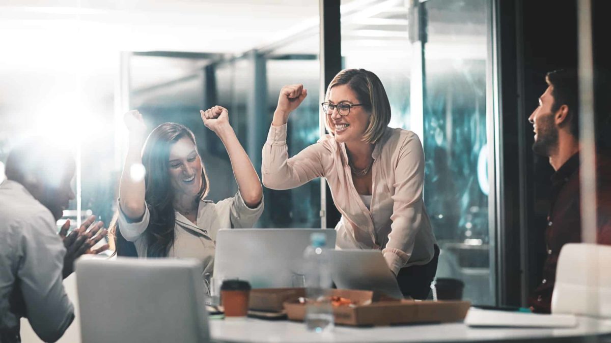 woman in an office with their fists up after winning