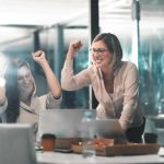 woman in an office with their fists up after winning
