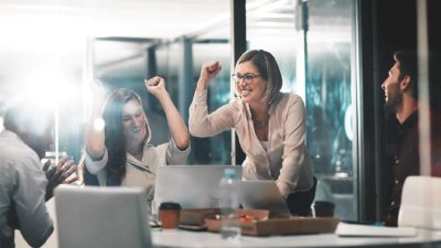 woman in an office with their fists up after winning