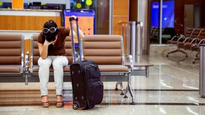 A traveller holds her head in her hands at the airport amid border closures and dflight disruptions