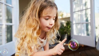 Young girl focused on a single bubble, finger outstretched ready to pop it.