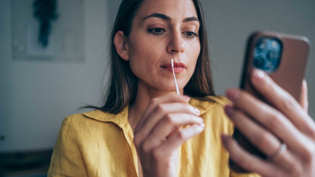 Woman prepares to insert a swab in her nose to test for COVID-19 at home.