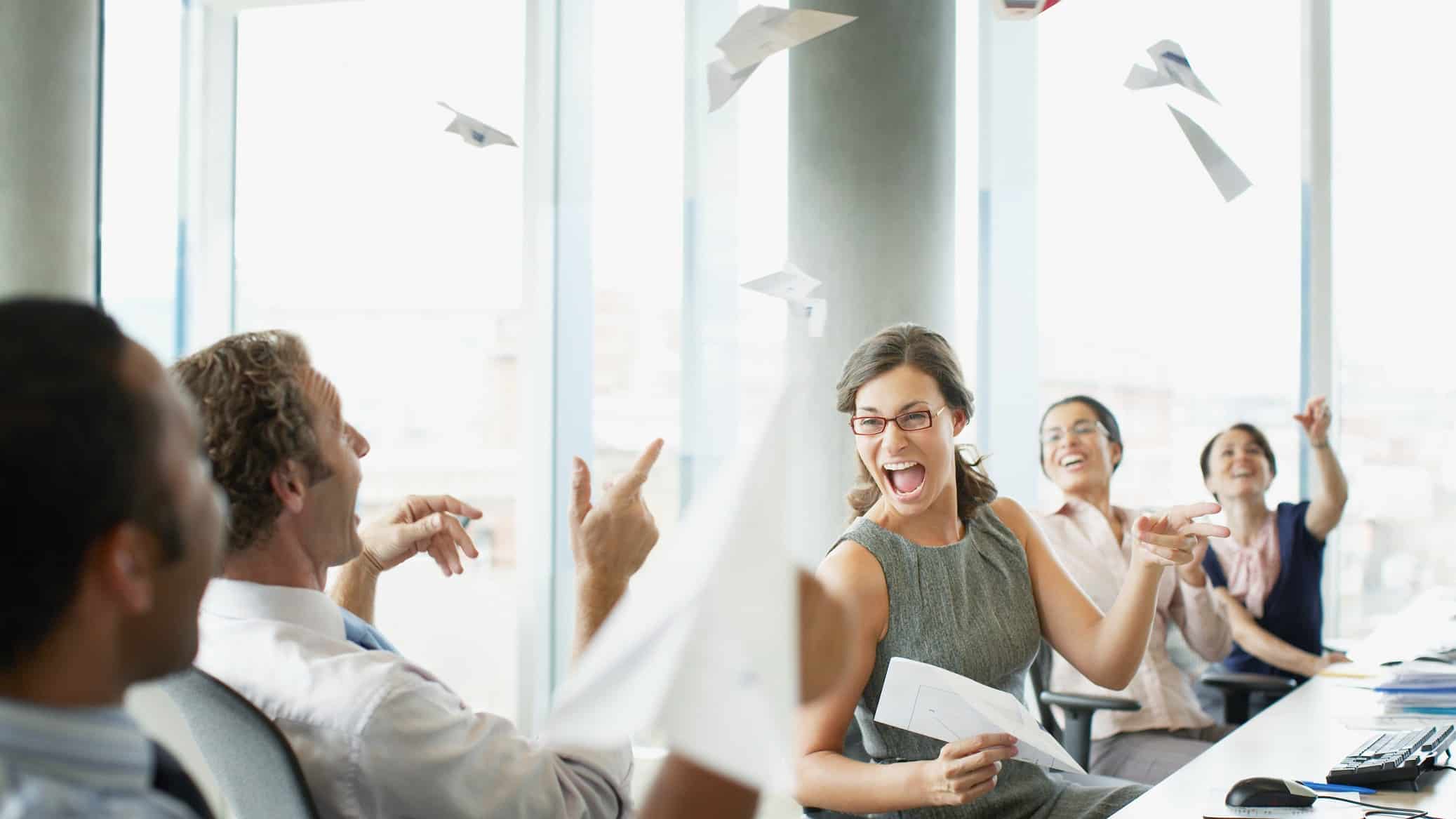 Businesspeople throwing paper airplanes in office