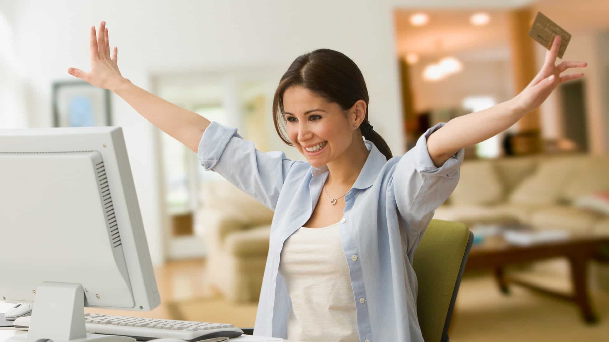 Cheering woman shopping online with credit card