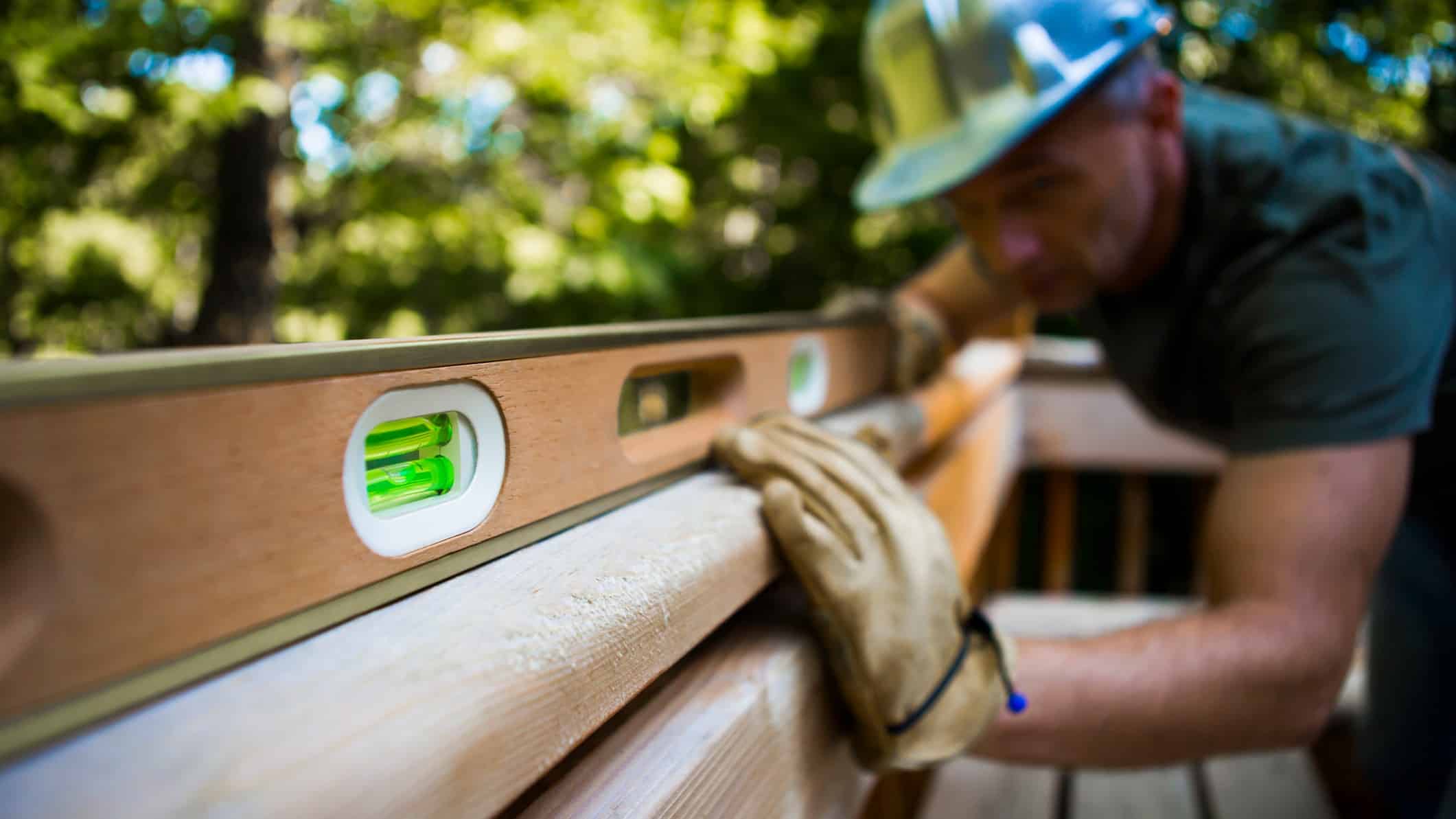 Builder eyes a spirit level on a piece of timber to ensure it's flat.
