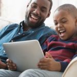 son playing game on iPad with dad watching netflix