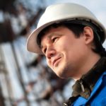 Mining plant worker in hard hat in front of equipment.