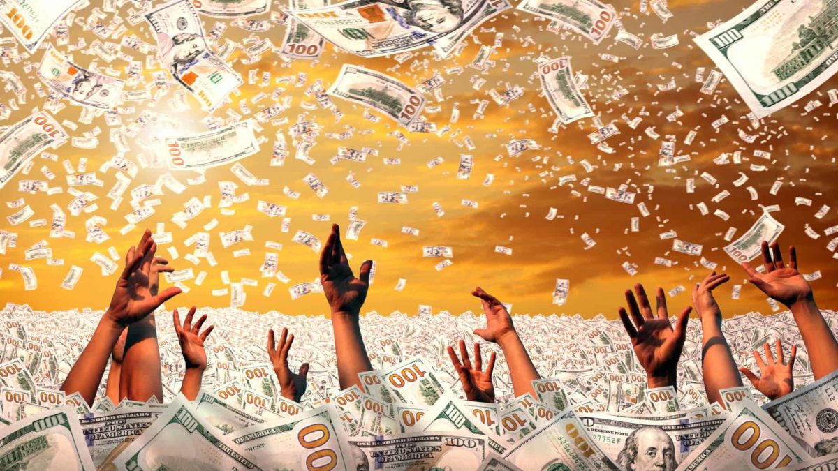 Hands reach out from under a sea of cash as more money swirls around in the sky, as the hands are grabbing for it.
