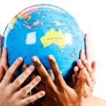 Map of Australia featured on a globe being held by many hands.