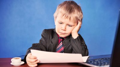 sad, dejected person looking at document with laptop and cup of tea nearby