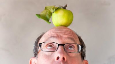 man looks up at apple on his head