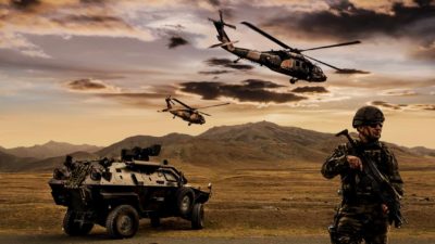 defence, military soldier standing with army land vehicle as helicopter flies overhead