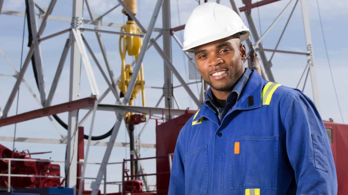 oil and gas worker in hard hard in front of oil and gas equipment