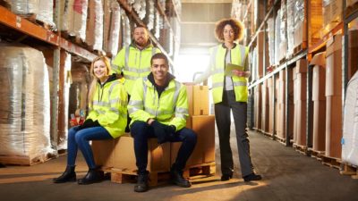 Logistic workers sitting amid pallets and stock in a warehouse.