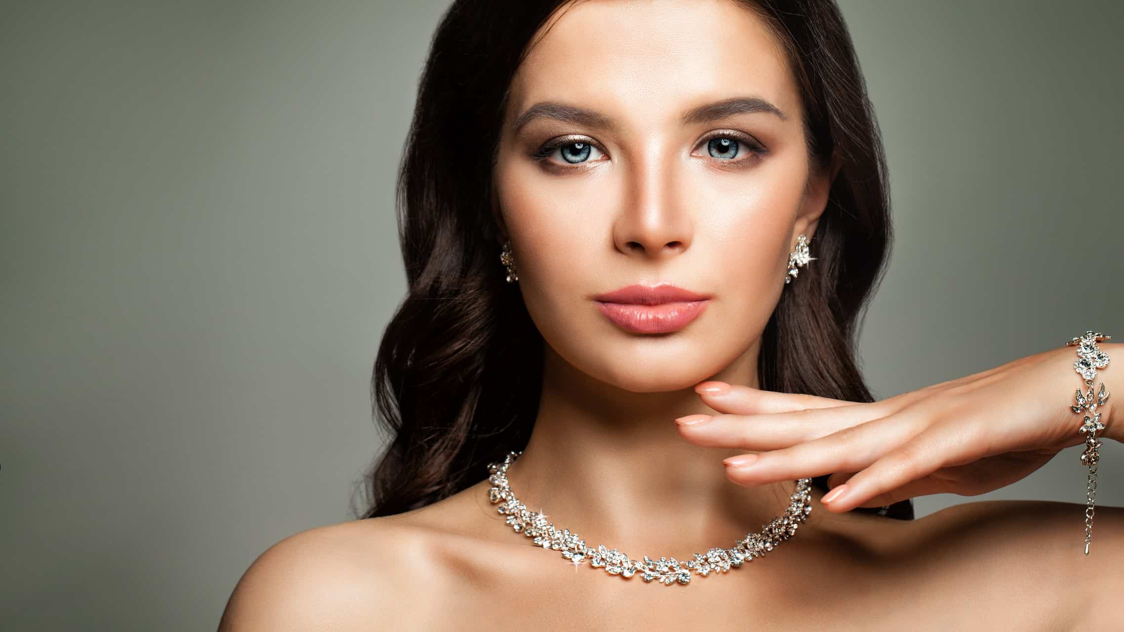 A woman stares directly ahead wearing diamond earrings, diamond necklace and diamond bracelet. as the Lovisa share price rises