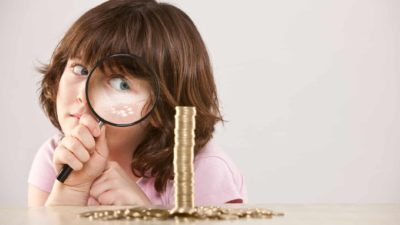 A girl looks through a microscope at money.