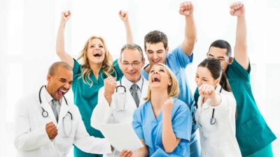 Group of doctors celebrate by pumping fists in the air